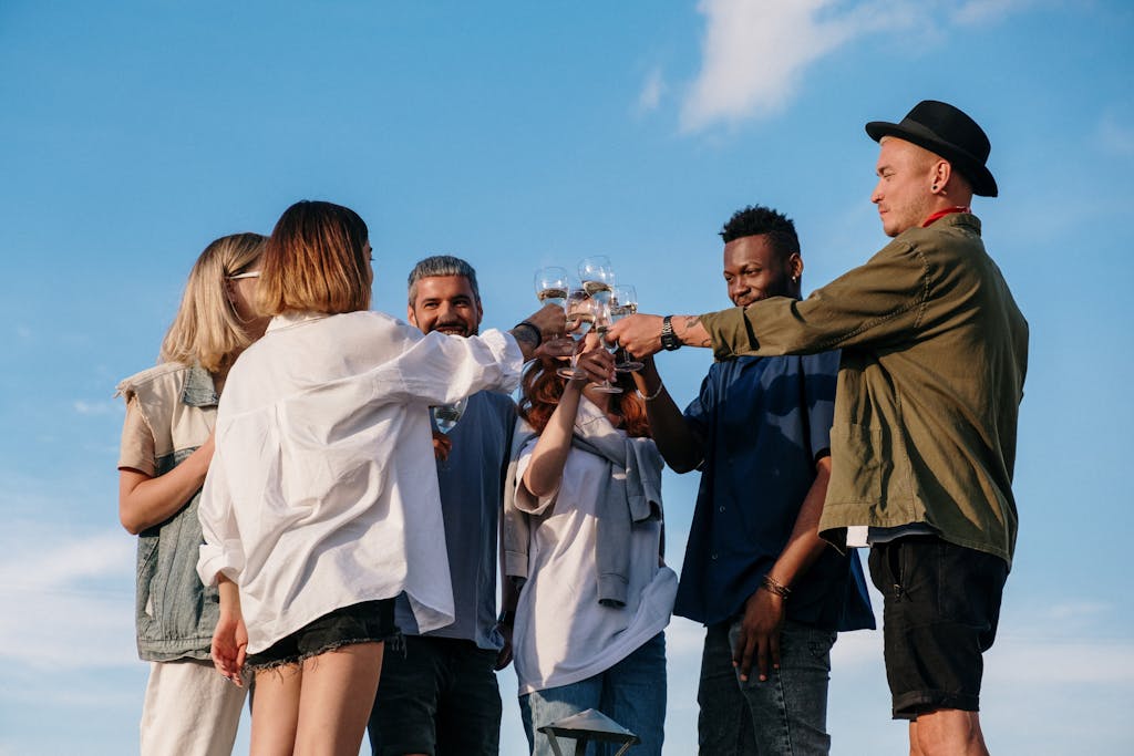 A joyful group of friends toasting together during a sunny outdoor gathering.